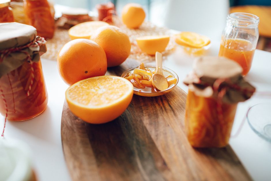 Mesa de madera con tarros de mermelada artesanal, fruta fresca y pan tostado